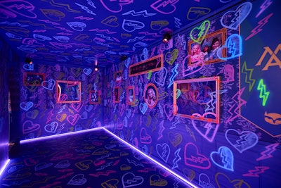 In Merlin’s Academy, guests found themselves surrounded by a library scene from the movie featuring school picture frames and mirrors with the song “What’s My Name (Red Version)” amplified throughout the space. The room pulsed like a heartbeat, revealing blacklight graffiti and a few hidden Easter eggs tied to the film.