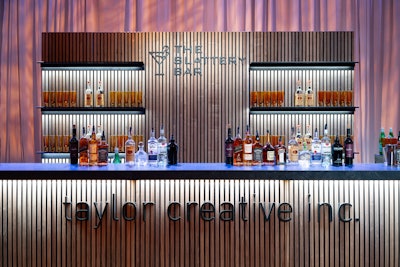 Taylor Creative's Slattery Collection features an elegant walnut finish, black slate laminate, black steel shelves, and LED lighting. It consists of a bar, corner, wall with shelves, and wall without shelving. All elements can be custom branded by an outside vendor for an additional charge. Items are available from the New York rental location for events nationwide. Pricing covers a one- to five-day rental period and starts at $275 per piece.