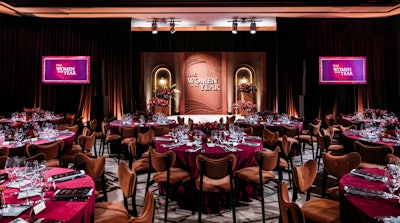 The intimate awards setting featured tonal shades of pinot and cognac velvet with pops of burgundy-hued florals and glowing candlelight in amber vessels. The 20-foot stage backdrop added an architectural moment as a focal point of the space; it included dimensional elements of plaster arched alcoves, walnut-stained extruded wood, and a cognac vegan leather fascia. Programming included special toasts from Nicole Kidman, Olivia Munn, and A’ja Wilson, among others, along with a string quartet-accompanied performance by Laufey.